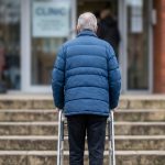 An elderly gentleman, with a walker is faced with a daunting set of steps to overcome